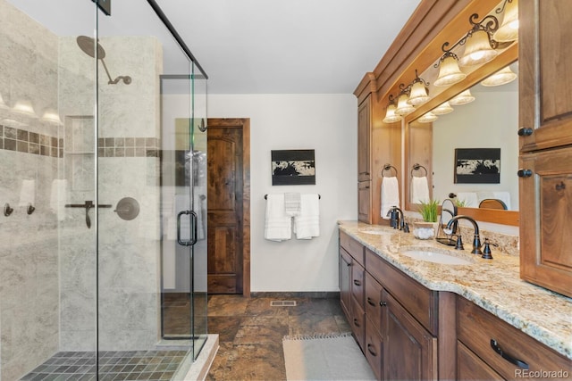 bathroom featuring double vanity, baseboards, a shower stall, and a sink