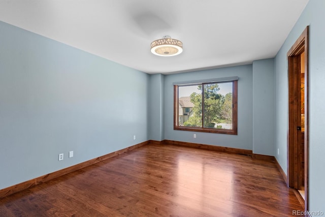 spare room with baseboards and wood finished floors