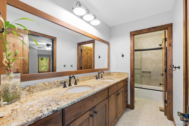 full bath featuring toilet, tile patterned floors, double vanity, and a sink