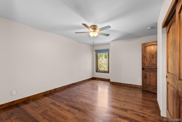 unfurnished bedroom featuring baseboards, a ceiling fan, and dark wood-style floors