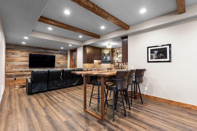 dining area featuring bar, beam ceiling, wood finished floors, recessed lighting, and baseboards