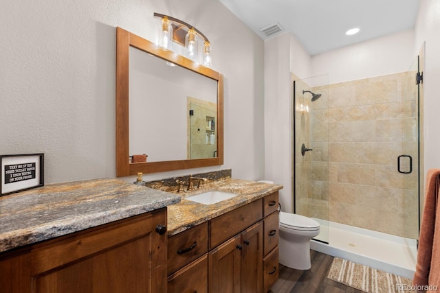 bathroom with a stall shower, toilet, visible vents, and wood finished floors
