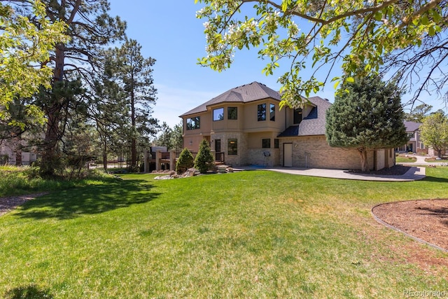 rear view of house with stucco siding, stone siding, and a lawn
