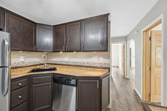 kitchen with stainless steel appliances, sink, dark brown cabinetry, and light wood-type flooring