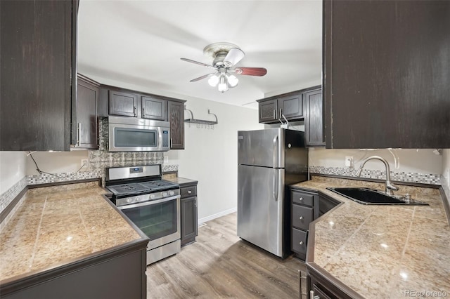 kitchen with sink, ceiling fan, light hardwood / wood-style floors, stainless steel appliances, and dark brown cabinets