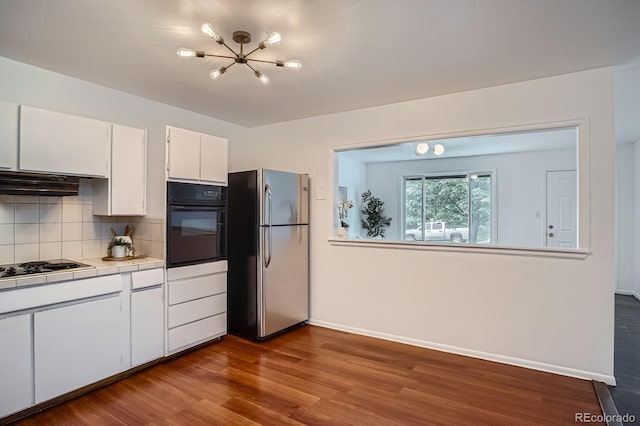 7618 Umatilla St, Denver, CO 80221 - kitchen featuring black appliances, tile countertops, a chandelier, white cabinetry, and decorative backsplash