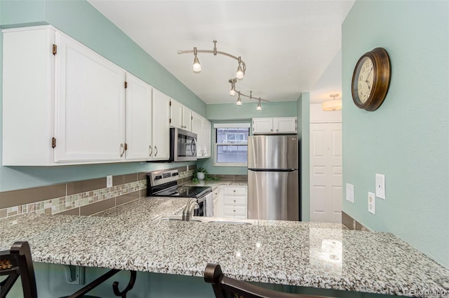 11147 W 17th Ave Unit 103, Lakewood, CO 80215 - kitchen featuring a peninsula, white cabinetry, appliances with stainless steel finishes, and light stone countertops