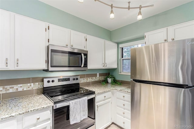 11147 W 17th Ave Unit 103, Lakewood, CO 80215 - kitchen with appliances with stainless steel finishes, white cabinets, light stone countertops, and tasteful backsplash