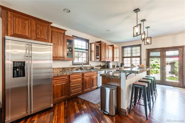 690 S Emerson St, Denver, CO 80209 - kitchen with appliances with stainless steel finishes, brown cabinets, a kitchen bar, dark wood-style floors, and glass insert cabinets