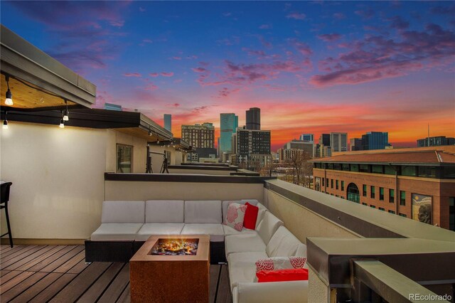 deck at dusk with an outdoor living space with a fire pit