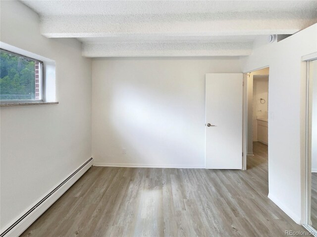 2401 S Gaylord St Unit 206, Denver, CO 80210 - unfurnished bedroom featuring a baseboard heating unit, light wood-style floors, and a textured ceiling