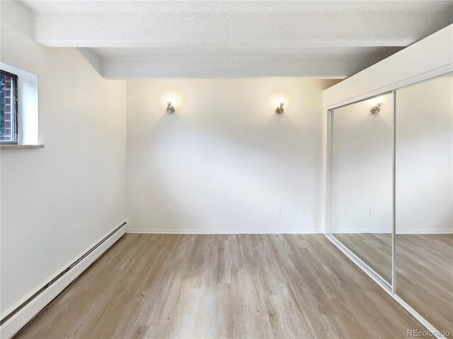 2401 S Gaylord St Unit 206, Denver, CO 80210 - unfurnished bedroom with baseboard heating, light wood-style flooring, a closet, and a textured ceiling