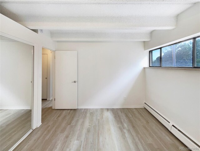 2401 S Gaylord St Unit 206, Denver, CO 80210 - unfurnished room with a baseboard heating unit, light wood-type flooring, and beamed ceiling