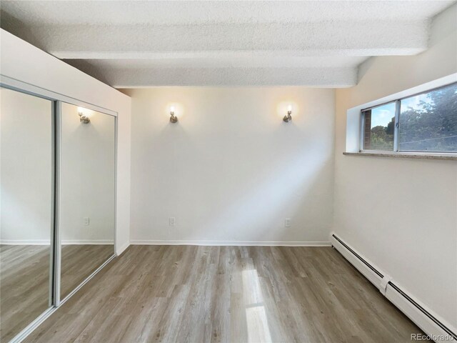 2401 S Gaylord St Unit 206, Denver, CO 80210 - unfurnished bedroom with a baseboard heating unit, wood finished floors, a closet, and a textured ceiling
