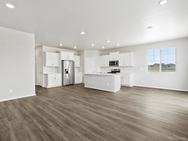 unfurnished living room with recessed lighting, baseboards, dark wood-type flooring, and a sink