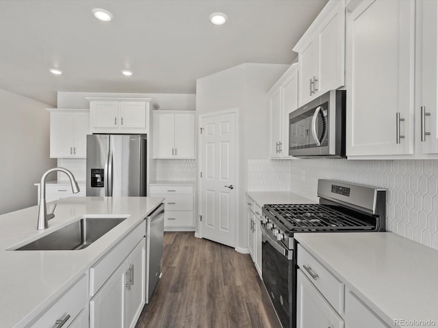 kitchen featuring stainless steel appliances, a sink, white cabinets, light countertops, and dark wood-style flooring