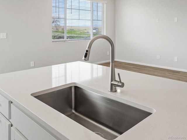 kitchen view of a sink, white cabinets, and light countertops