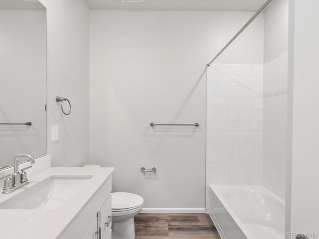 bathroom with wood finished floors, baseboards, toilet, vanity, and bathing tub / shower combination
