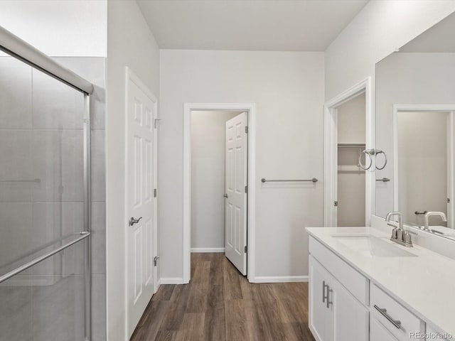 full bath featuring wood finished floors, a shower stall, vanity, a closet, and baseboards