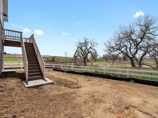 view of yard featuring stairs, fence, and a rural view