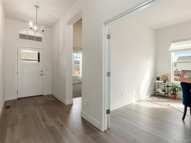 foyer featuring a chandelier, wood finished floors, visible vents, and baseboards