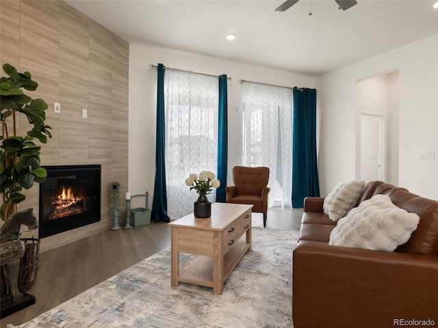 living area with ceiling fan, a fireplace, and wood finished floors