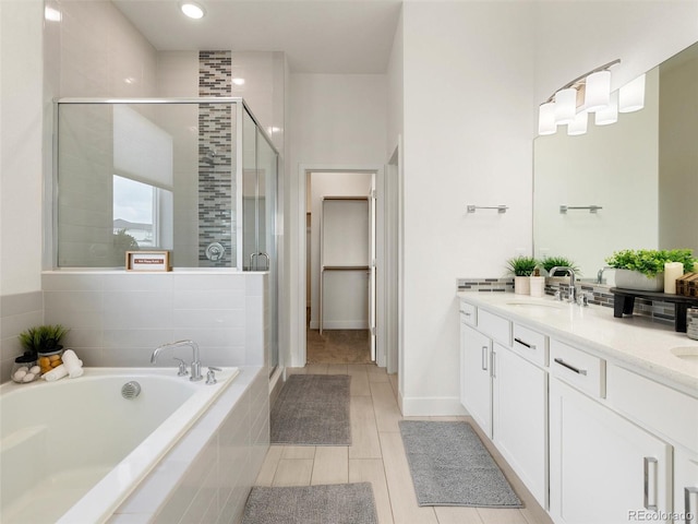 full bath featuring double vanity, a garden tub, a sink, and a stall shower