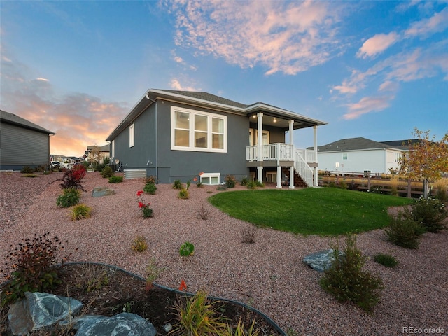 back of property with stucco siding, a lawn, fence, and stairs