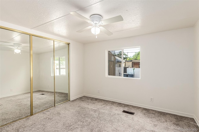 unfurnished bedroom featuring ceiling fan, carpet floors, a closet, and a textured ceiling