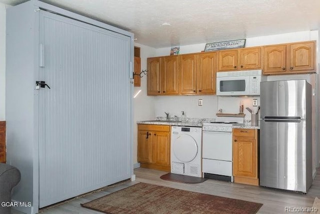 62927 US Highway 40 Unit 127, Granby, CO 80446 - kitchen with white appliances, washer / dryer, light countertops, and light wood-style flooring
