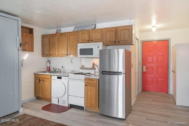 62927 US Highway 40 Unit 127, Granby, CO 80446 - kitchen with white appliances, light wood-style floors, washer / clothes dryer, and brown cabinets