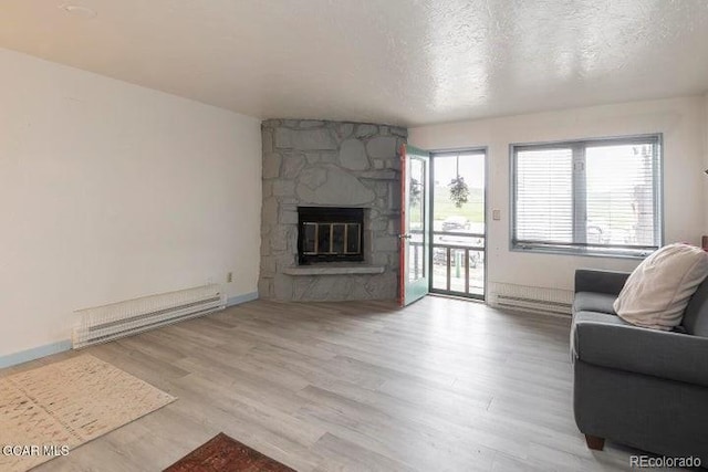 62927 US Highway 40 Unit 127, Granby, CO 80446 - living room featuring a baseboard radiator, wood finished floors, a textured ceiling, and a stone fireplace
