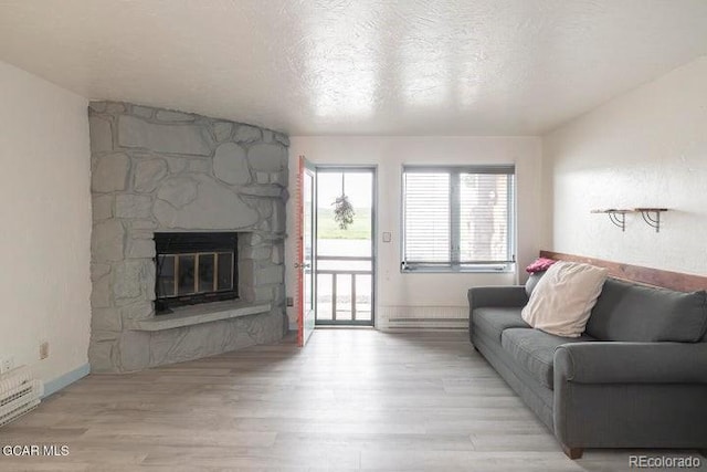 62927 US Highway 40 Unit 127, Granby, CO 80446 - living area with wood finished floors, a stone fireplace, a textured ceiling, and a baseboard radiator