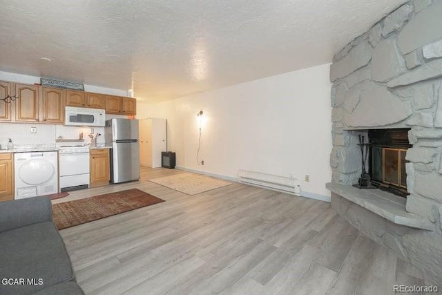 62927 US Highway 40 Unit 127, Granby, CO 80446 - unfurnished living room featuring baseboard heating, light wood finished floors, a textured ceiling, a stone fireplace, and washer / clothes dryer