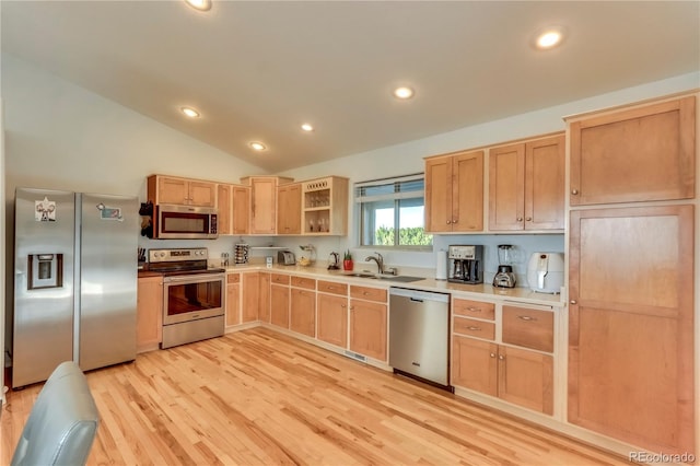 kitchen with light wood-type flooring, sink, vaulted ceiling, stainless steel appliances, and light brown cabinetry