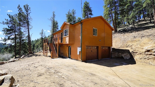 325 Bob Cat Trl, Bailey, CO 80421 - view of side of home with an attached garage, stairway, a wooden deck, and driveway
