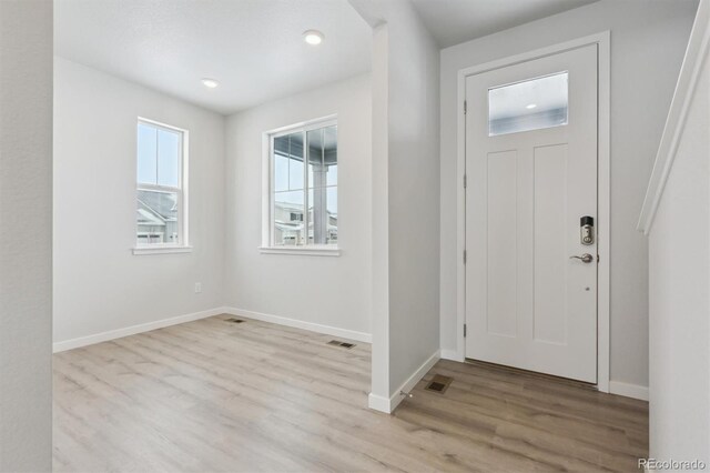 foyer featuring light wood finished floors, baseboards, and visible vents