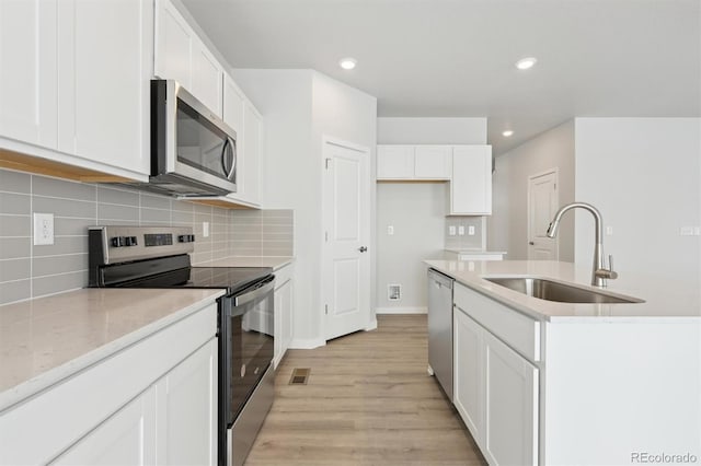 kitchen with tasteful backsplash, stainless steel appliances, light wood-type flooring, white cabinetry, and a sink