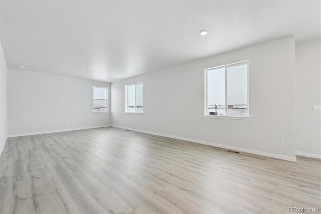 spare room featuring visible vents, light wood-style flooring, and baseboards