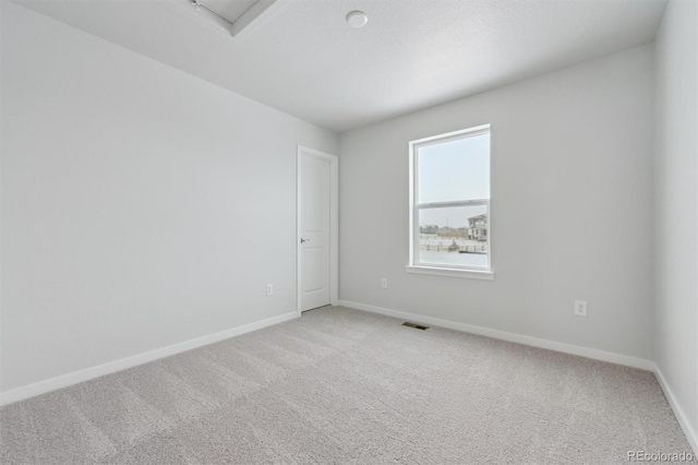 spare room with baseboards, visible vents, and light colored carpet