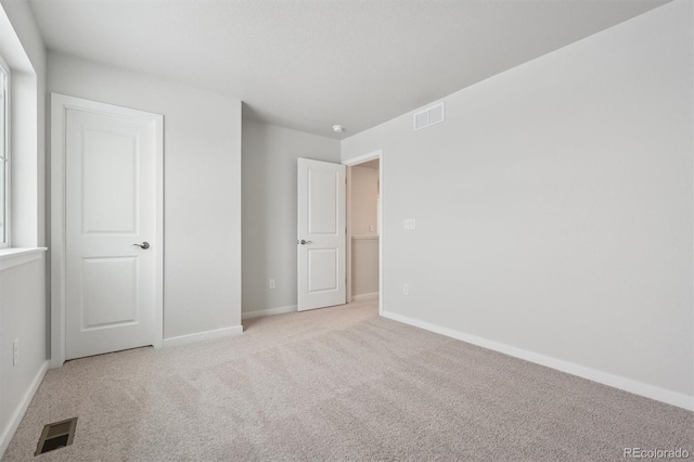 unfurnished bedroom featuring baseboards, visible vents, and light colored carpet