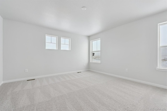 carpeted spare room featuring visible vents and baseboards