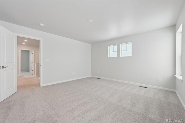 empty room featuring baseboards, visible vents, and light colored carpet