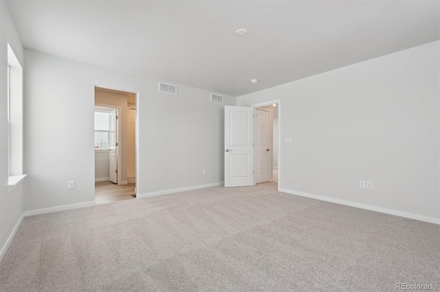 unfurnished bedroom featuring light colored carpet, visible vents, and baseboards