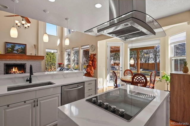 kitchen featuring stainless steel dishwasher, a brick fireplace, a sink, black electric cooktop, and exhaust hood