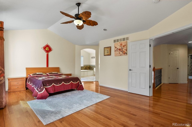 bedroom featuring arched walkways, visible vents, lofted ceiling, and wood finished floors