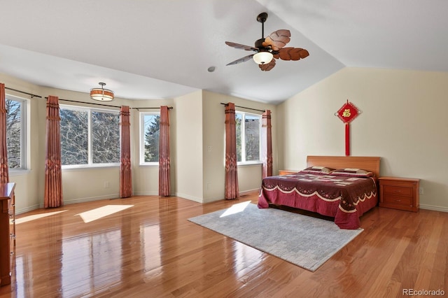 bedroom with lofted ceiling, multiple windows, baseboards, and wood finished floors