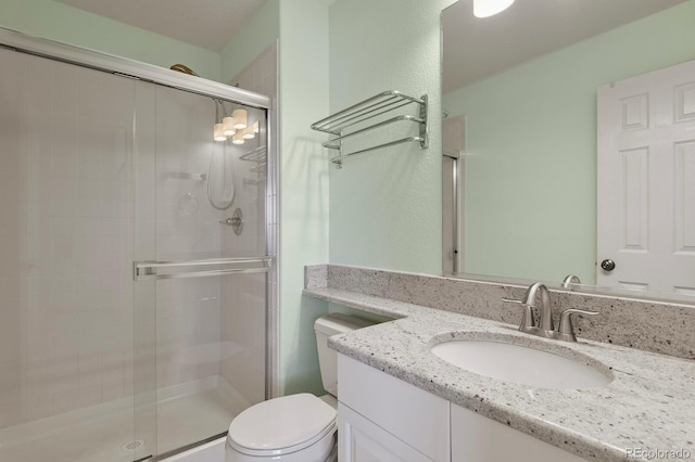 full bathroom with vanity, a shower stall, and toilet