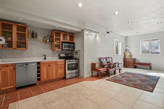 kitchen featuring light tile patterned floors, decorative backsplash, glass insert cabinets, stainless steel appliances, and light countertops