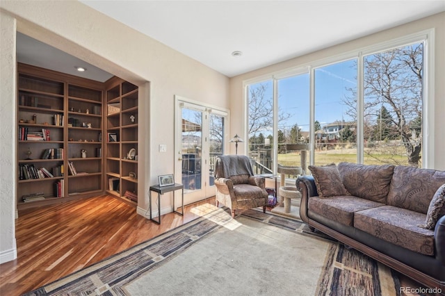 living area featuring baseboards, built in features, and wood finished floors